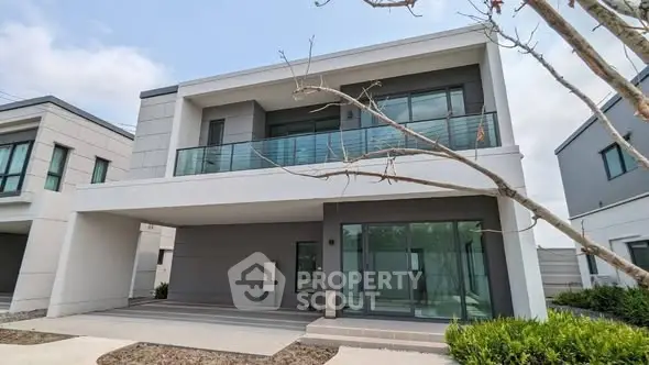 Modern two-story house with large windows and balcony in a suburban neighborhood.