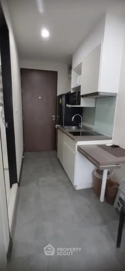 Modern compact kitchen with sleek cabinetry and integrated appliances in a contemporary apartment.