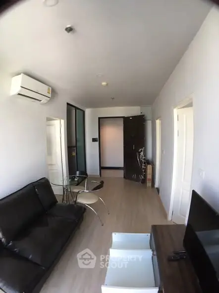 Modern living room with sleek black sofa and wall-mounted air conditioner