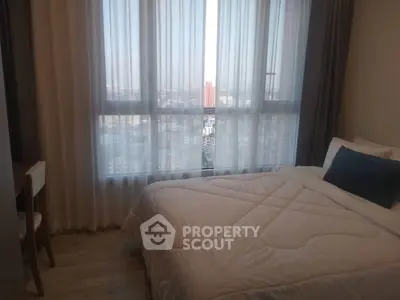 Cozy bedroom with large window offering city view and natural light.