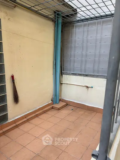 Cozy small balcony with tiled floor and metal railing, perfect for urban living.