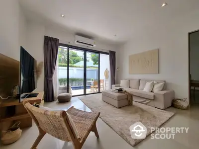 Modern living room with elegant decor and pool view, featuring cozy seating and natural light.