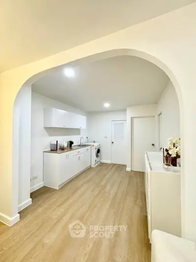 Spacious kitchen with modern white cabinetry and wood flooring