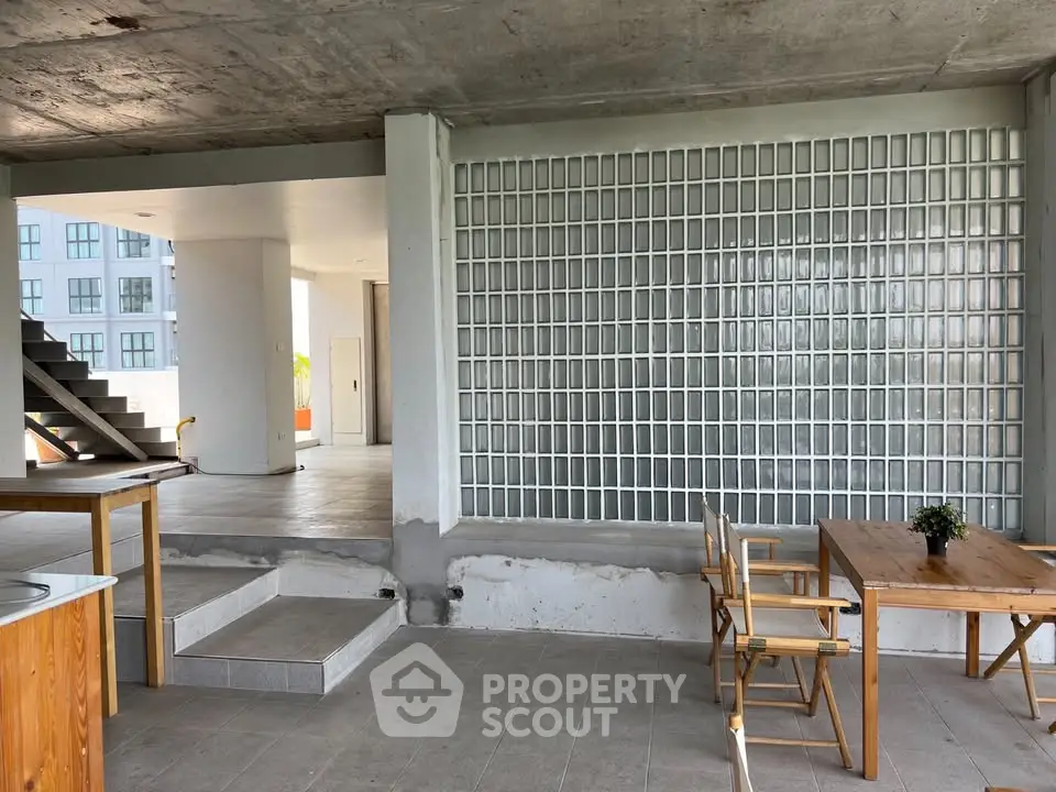 Modern open-plan interior with glass block wall and wooden furniture, showcasing industrial design elements.