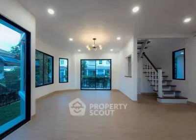 Spacious modern living room with large windows and elegant staircase