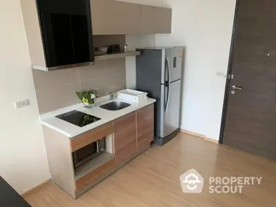 Modern compact kitchen with sleek appliances and wooden cabinetry in a stylish apartment.