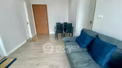 Modern living room with cozy sofa and dining area, featuring sleek wooden flooring and minimalist decor.