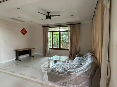 Spacious living room with large window and modern furnishings in a serene setting.