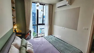 Modern bedroom with city view, featuring stylish decor and natural light.