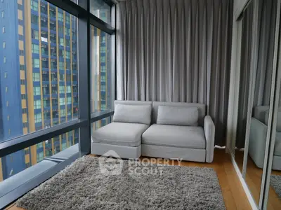 Modern living room with floor-to-ceiling windows and cozy gray sofa in urban apartment.
