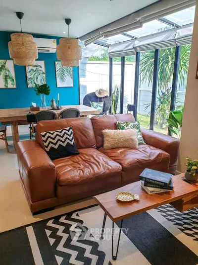 Stylish living room with leather sofa, large windows, and modern decor in a bright, inviting space.