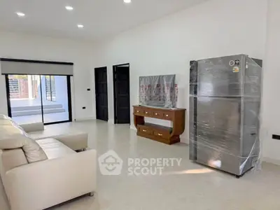 Spacious living room with modern furniture and large refrigerator, perfect for comfortable living.