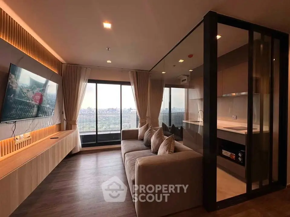 Modern living room with open kitchen and city view, featuring sleek design and cozy ambiance.