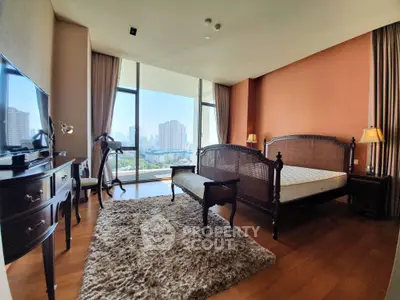 Luxurious bedroom with elegant furniture and stunning city view, featuring large windows and warm decor.