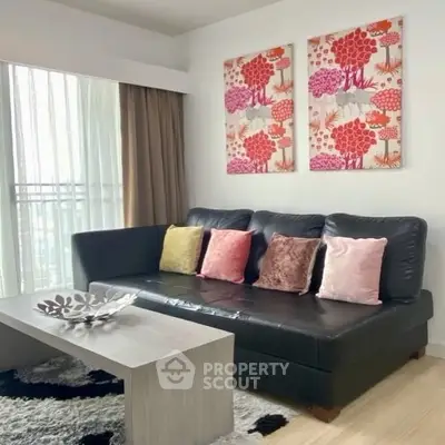 Stylish living room with modern black sofa and colorful cushions, bright artwork, and natural light.