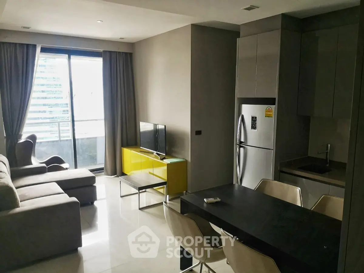 Modern living room with open kitchen and balcony view in urban apartment.