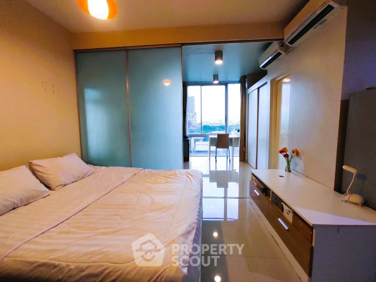 Modern bedroom with large bed, sliding glass doors, and city view.