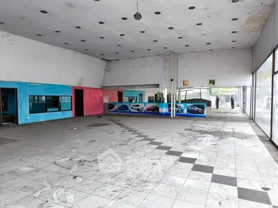 Spacious commercial property with large windows and tiled flooring, ideal for showroom or retail space.