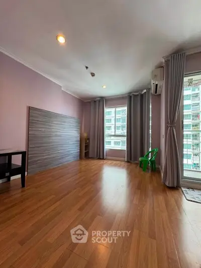Spacious unfurnished room with wooden flooring and large windows in modern apartment.