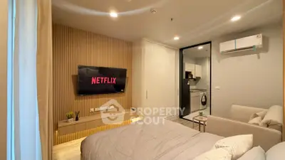 Modern bedroom with wall-mounted TV and cozy decor in a stylish apartment.