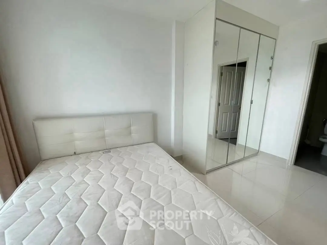 Spacious bedroom with mirrored wardrobe and modern minimalist design.