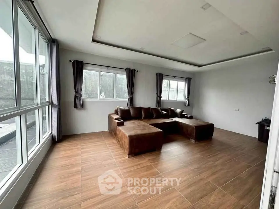 Spacious living room with modern brown sectional sofa and large windows