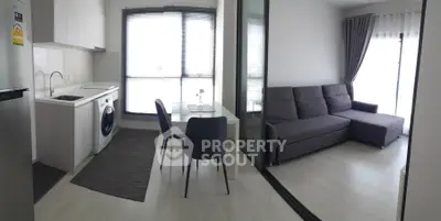 Modern apartment with open kitchen and cozy living area, featuring sleek furniture and natural light.