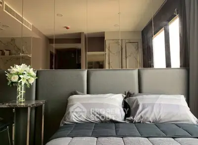 Luxurious bedroom with elegant decor and mirrored wall in modern apartment.