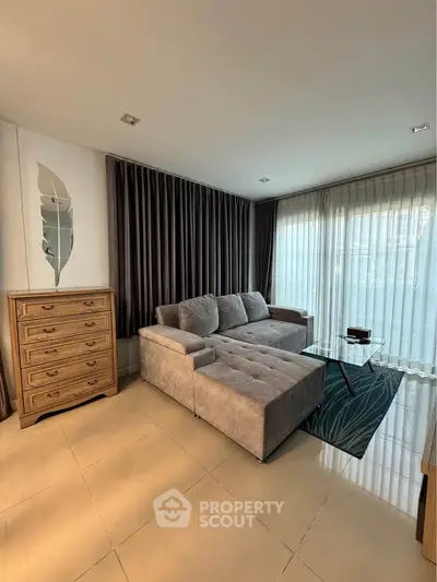 Spacious living room with modern sofa and elegant decor, featuring large windows and natural light.