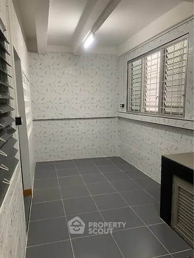 Spacious tiled utility room with large windows and ample natural light.