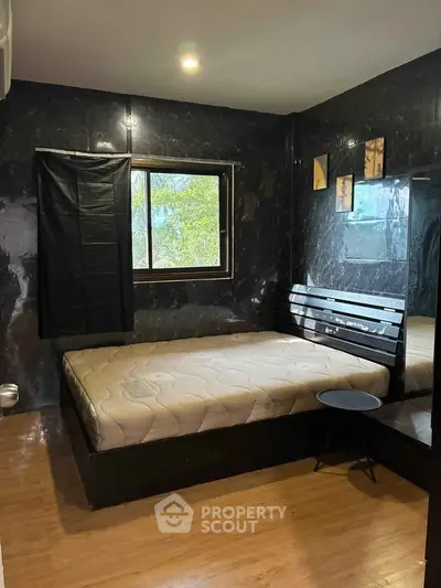 Modern bedroom with sleek black marble walls and large window offering natural light.