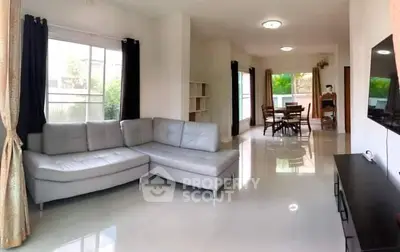 Spacious living room with modern gray sofa and dining area, perfect for family gatherings.