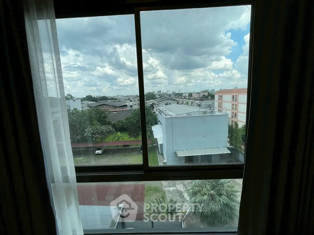 Stunning urban view from a window showcasing cityscape and lush greenery.