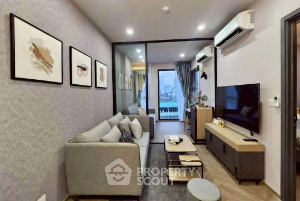 Modern living room with stylish decor and large TV, featuring a cozy sofa and air conditioning.