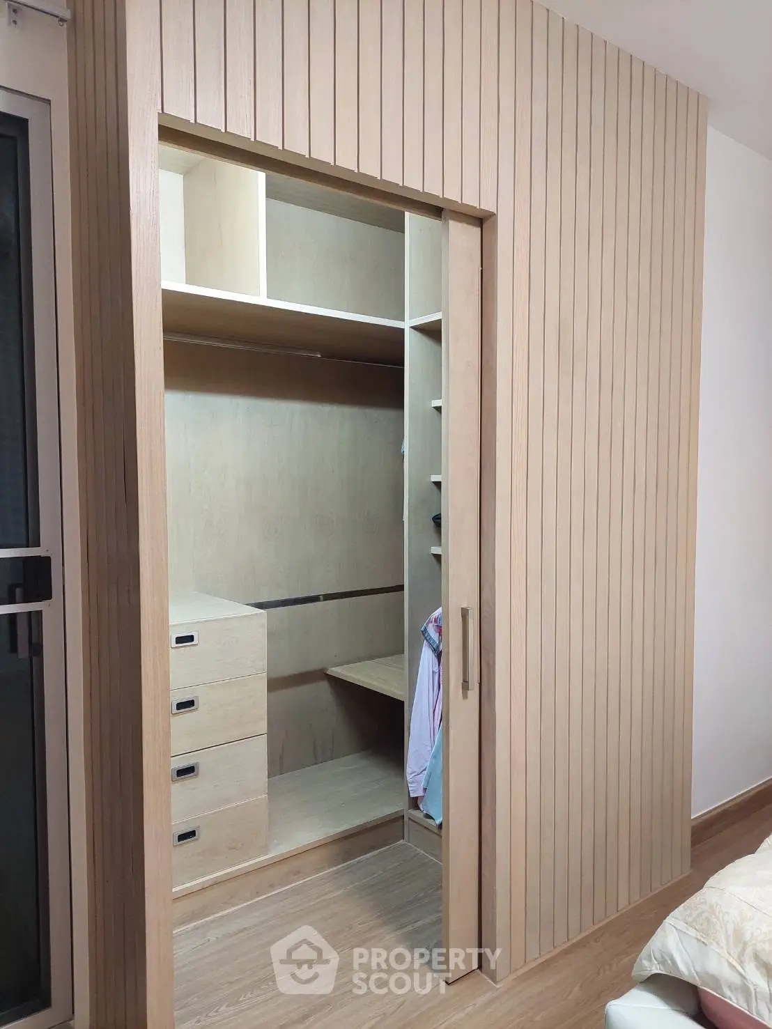 Spacious walk-in closet with wooden finish and ample storage space in modern bedroom.