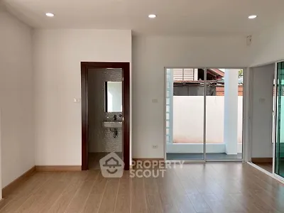 Spacious modern living room with wooden flooring and sliding glass doors leading to a private outdoor area.