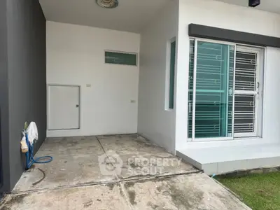 Modern house exterior with sleek sliding glass door and concrete patio