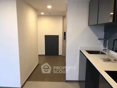 Modern kitchen with sleek cabinetry and hallway view in contemporary apartment.