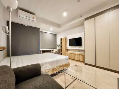 Modern bedroom with sleek furniture and wall-mounted TV, featuring a minimalist design and ample storage space.