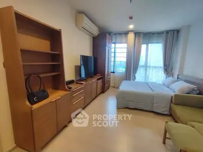 Spacious bedroom with modern furniture and large window offering natural light.