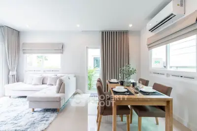 Modern living room with dining area, featuring elegant decor and natural light.