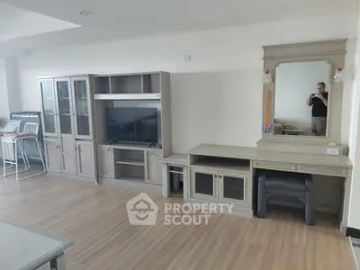 Spacious living room with modern wooden furniture and large TV unit, perfect for relaxation.