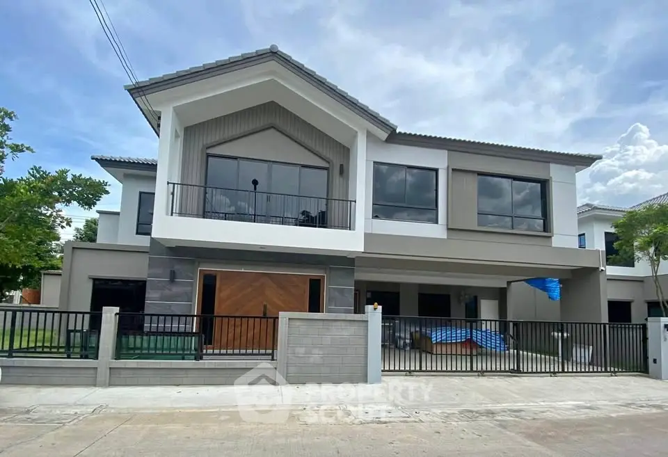 Modern two-story house with large windows and a spacious balcony.