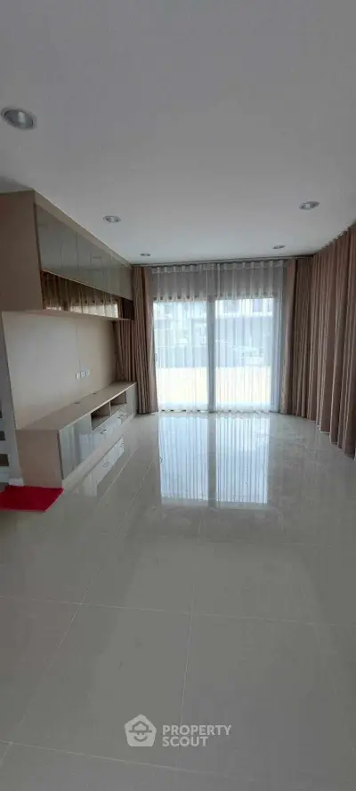 Spacious living room with large windows and modern built-in storage, perfect for natural light lovers.