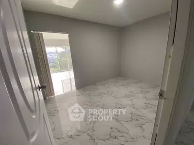 Spacious empty room with marble flooring and large window for natural light.