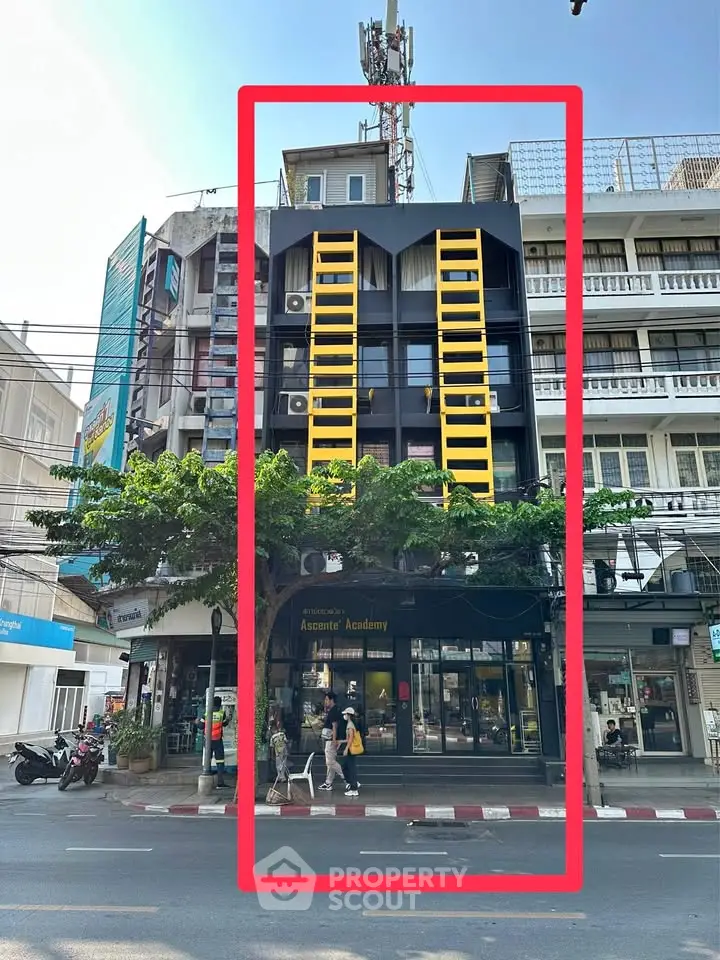 Modern urban building with striking yellow accents and street-level commercial space.