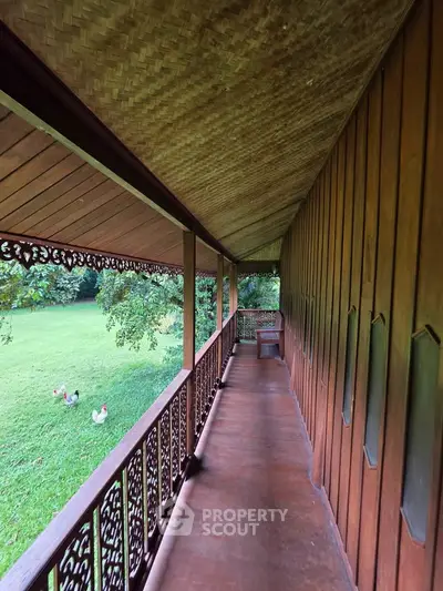 Charming wooden balcony with intricate railing overlooking lush green garden