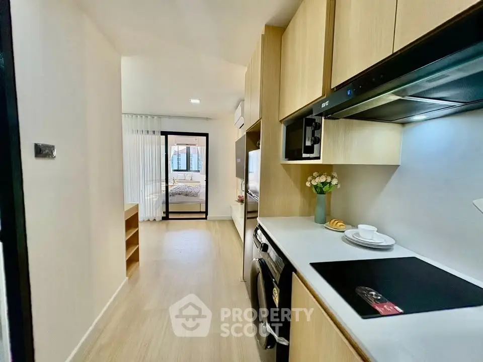 Modern kitchen with sleek appliances and view into cozy bedroom