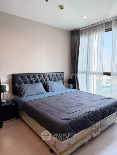 Modern bedroom with large window and stylish decor in a high-rise apartment.