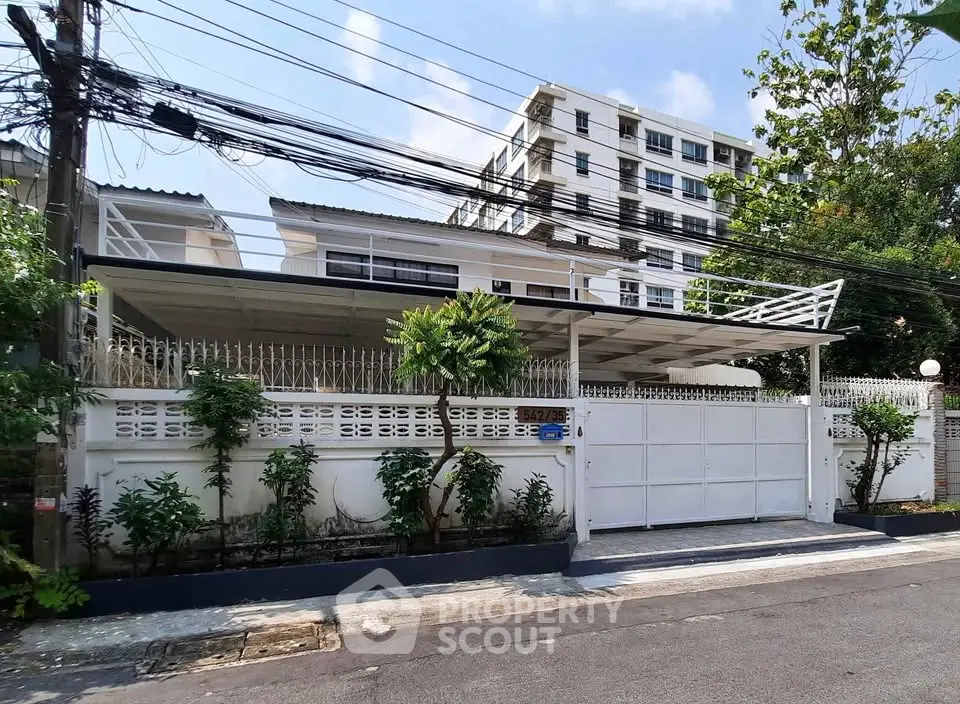 Charming residential property with gated entrance and lush greenery in a serene neighborhood.